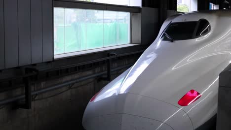 close-up of a high-speed train's aerodynamic nose inside a station tunnel.