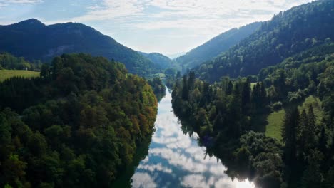 Blue-reflecting-river-between-clad-mountains-in-an-idyllic-landscape-bathed-in-sunlight