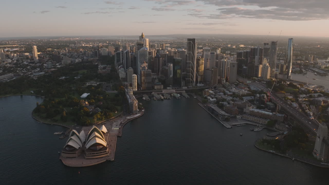 sydney opera house y sydney downtown city skyline, rascacielos, australia, durante la hora de oro del atardecer, con sombras largas, cinematográfico estableciendo gran ángulo, aéreo