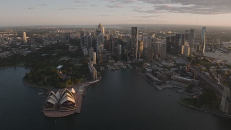 sydney opera house and sydney downtown city skyline, skyscrapers, australia, during sunset golden hour, with long shadows, cinematic establishing wide angle, aerial