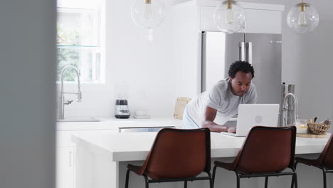 Una-Pareja-En-Pijama-Parada-En-La-Cocina-Trabajando-Desde-Casa-En-Una-Computadora-Portátil