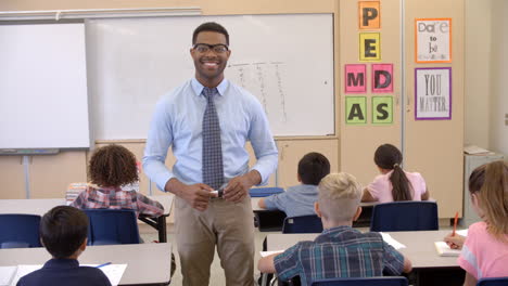 happy black male teacher walking through class toward camera