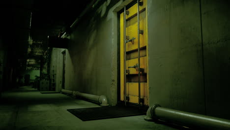 a dark corridor with a yellow security door at the end