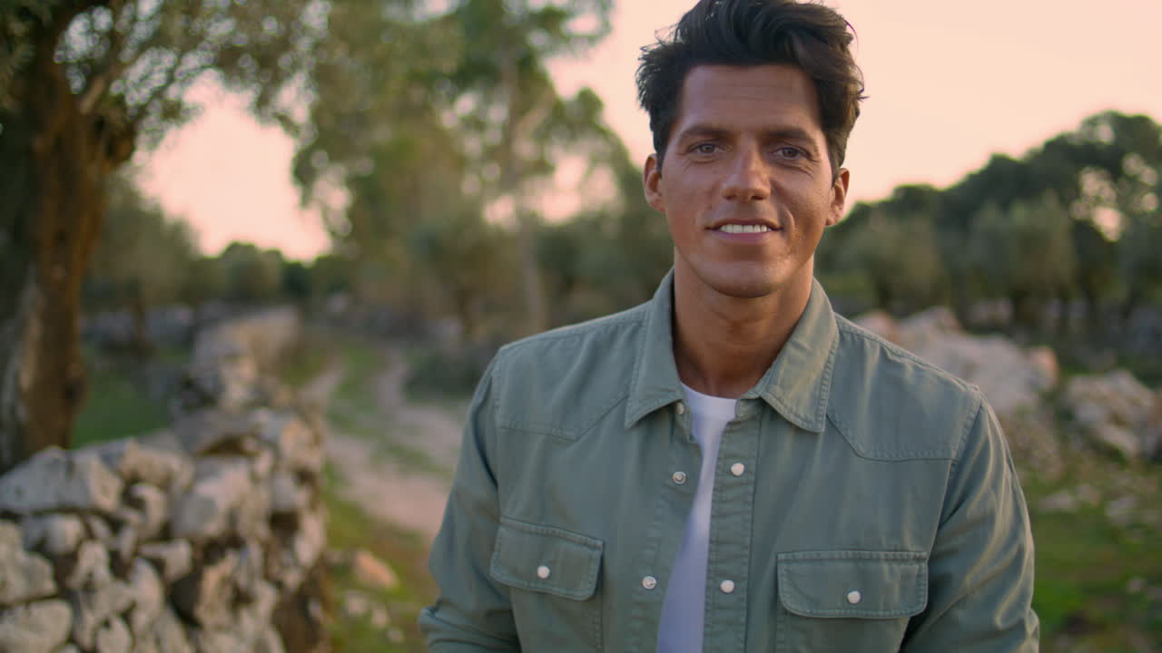 쾌활한 모델이 나무에 카메라를 쳐다보고 있습니다. 식물의 초상화. 자연에서 휴식을 취하는 사람