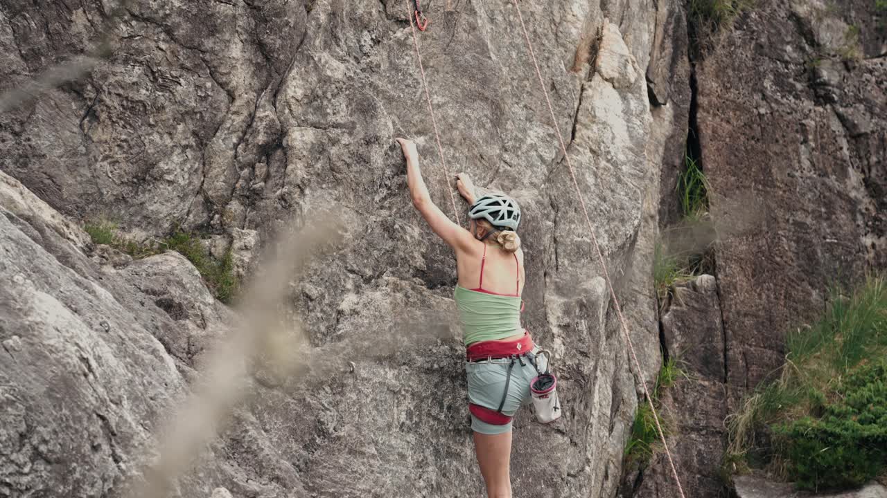 mujer preparándose para escalar una pared de piedra, vista de atrás