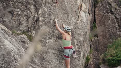 Woman-preparing-to-climb-stone-wall,-back-view