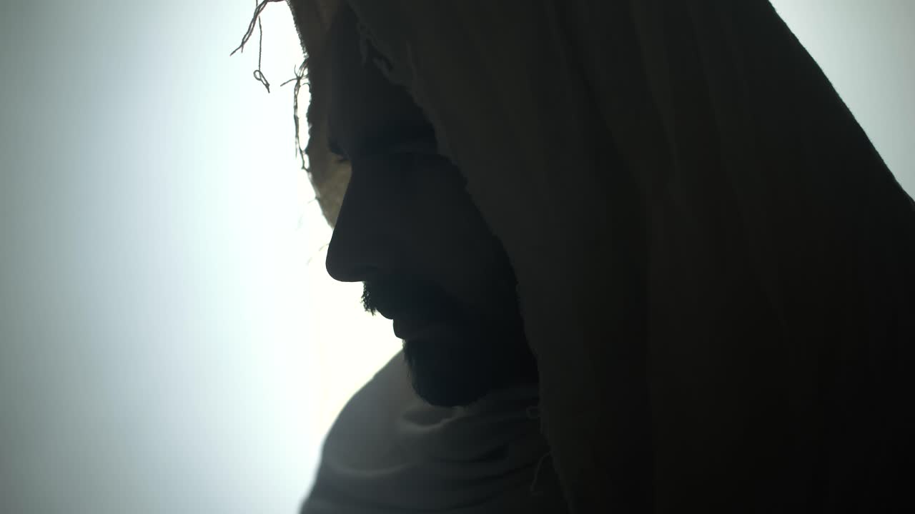 The face of the resurrected Jesus Christ standing inside the tomb in bright, dramatic, glowing, holy light as representation of the Easter Sunday resurrection in cinematic slow motion.