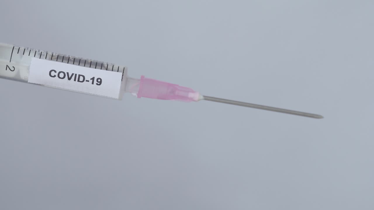 mano de un médico quita la tapa de la aguja de la jeringa con la vacuna covid-19