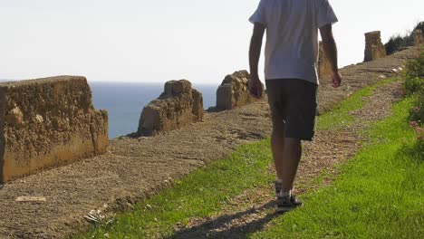 Hombre-Caminando-Por-El-Sendero-Del-Acantilado-Con-Vista-Al-Océano