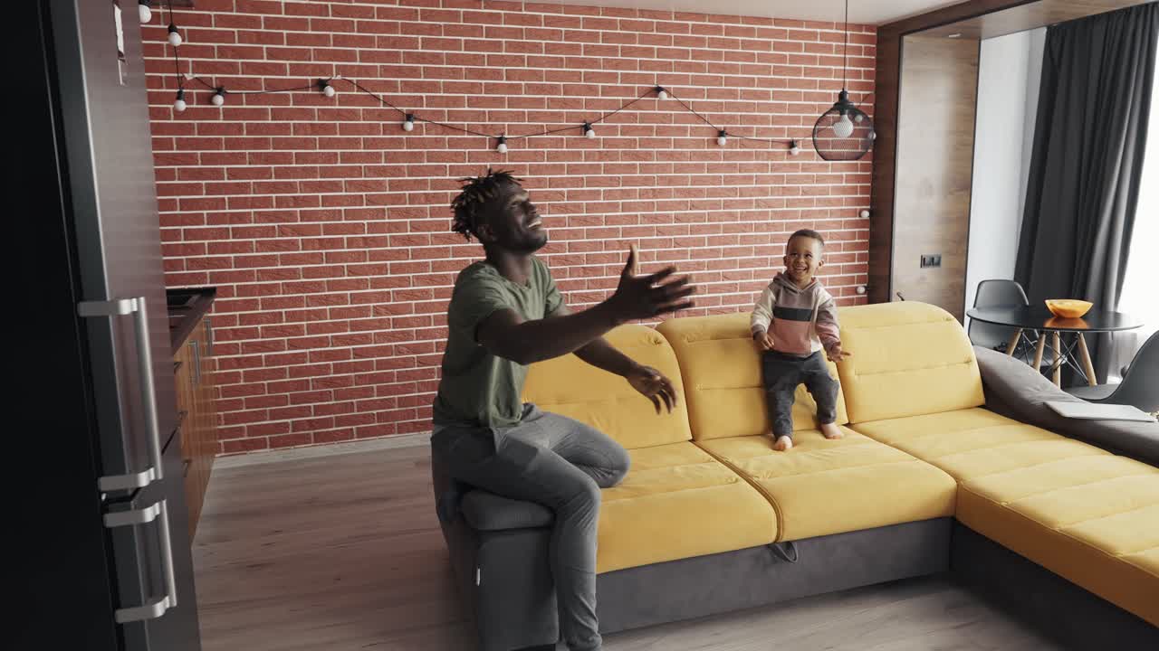 African-American father playing with little boy, throwing balloon to each other