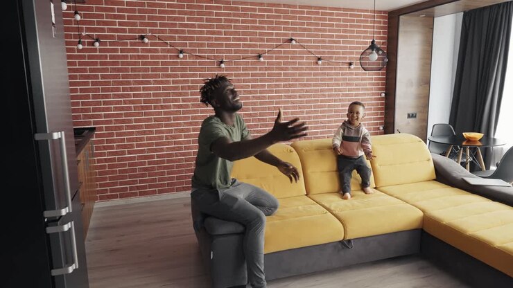 African-American father playing with little boy, throwing balloon to each other