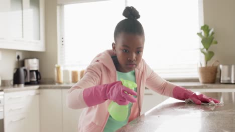 feliz niña afroamericana limpiando la encimera en la cocina, en cámara lenta
