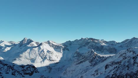 aerial view overlooking rocky mountain ranges, snowy winter landscape - reverse, drone shot