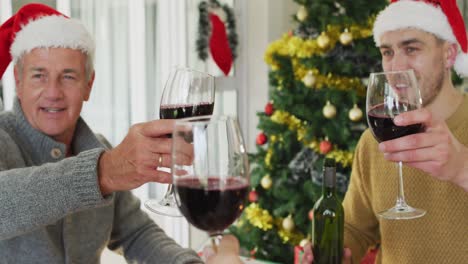 Feliz-Familia-Caucásica-De-Varias-Generaciones-Usando-Sombreros-De-Santa,-Comiendo-Navidad,-Haciendo-Tostadas