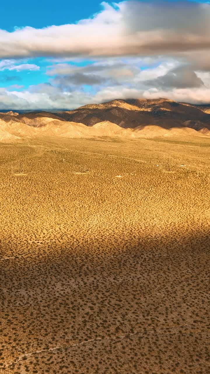 Spotted deserted landscape of Nevada on hot sunny day. Drone rising above the scenery. Rocks covered with clouds at backdrop. Vertical video