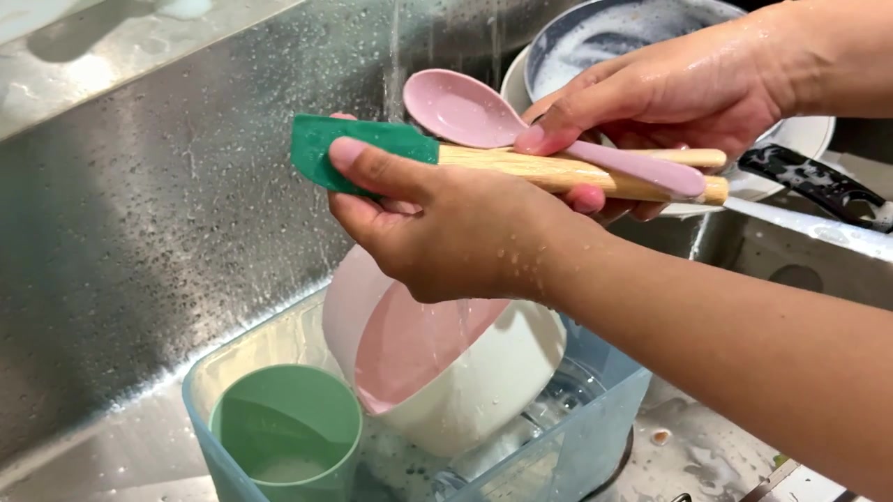 Lavare a mano un cucchiaio sotto l'acqua corrente in un lavello da cucina, evidenziando il lavaggio dei piatti, l'igiene, la pulizia e le faccende domestiche quotidiane.