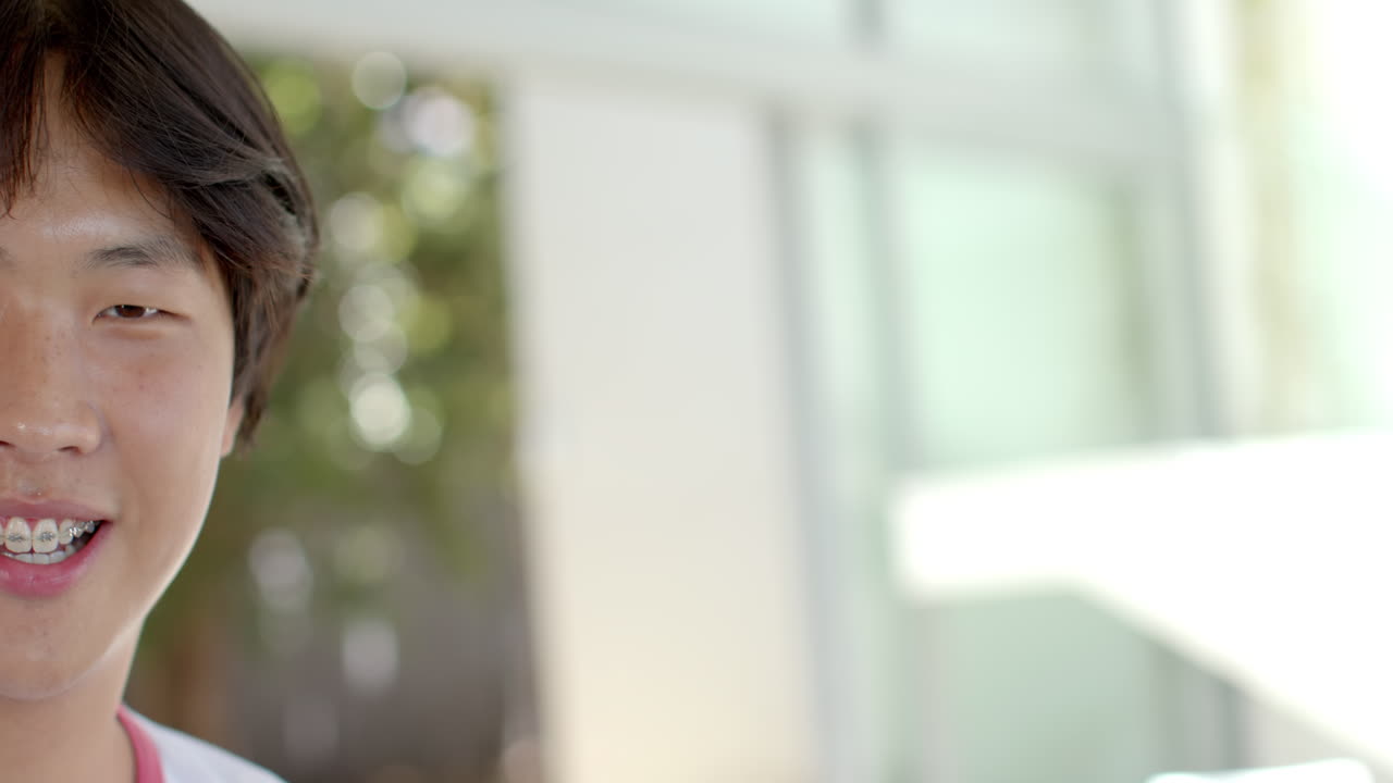 아시아 학생, 검은 머리, 분홍색 셔츠를 입고 미소 짓고, 카메라를 쳐다보고