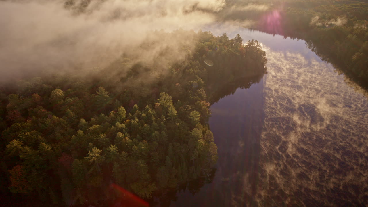 Aerial cinematic pass over water with mist glowing in dawn light