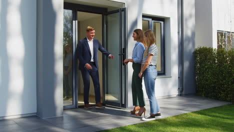 real estate agent welcomes two women to view a modern house