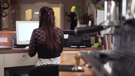 Girl-using-computer-and-lever-coffee-maker-in-foreground,-rare-slider-shot