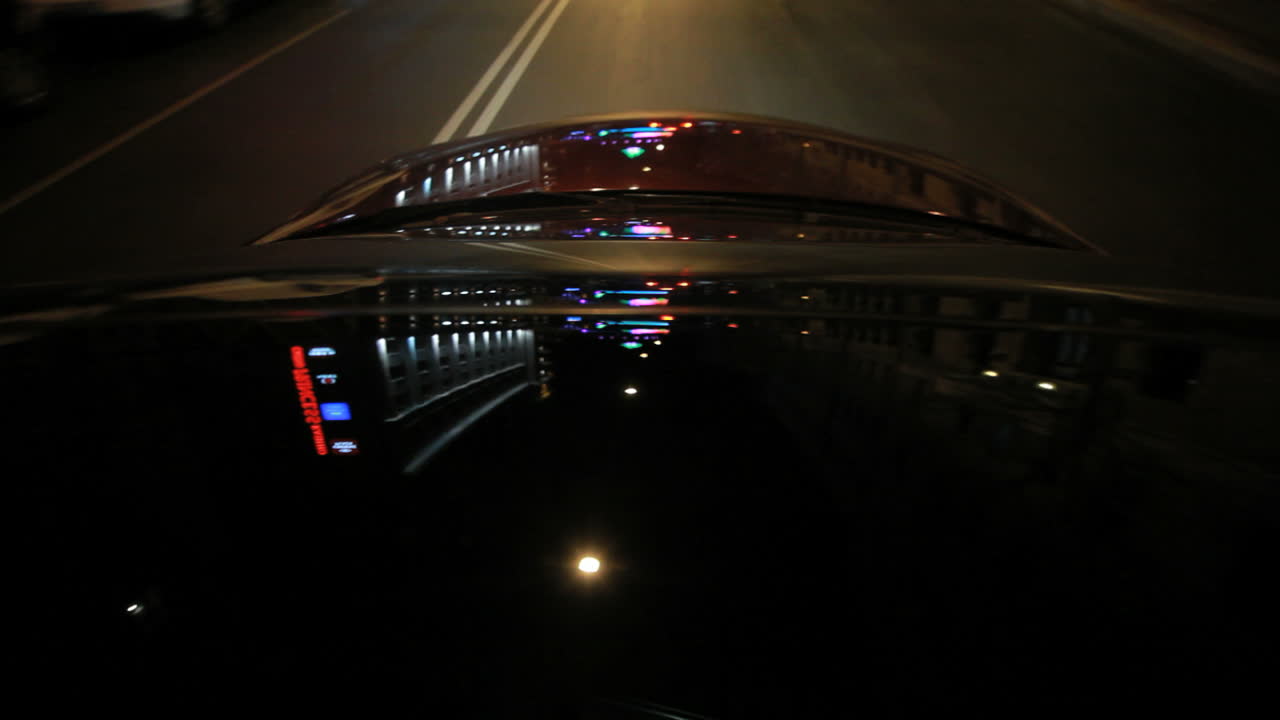 iluminación de la calle en el capó del coche. reflejos de luz en el vidrio del coche y el capó