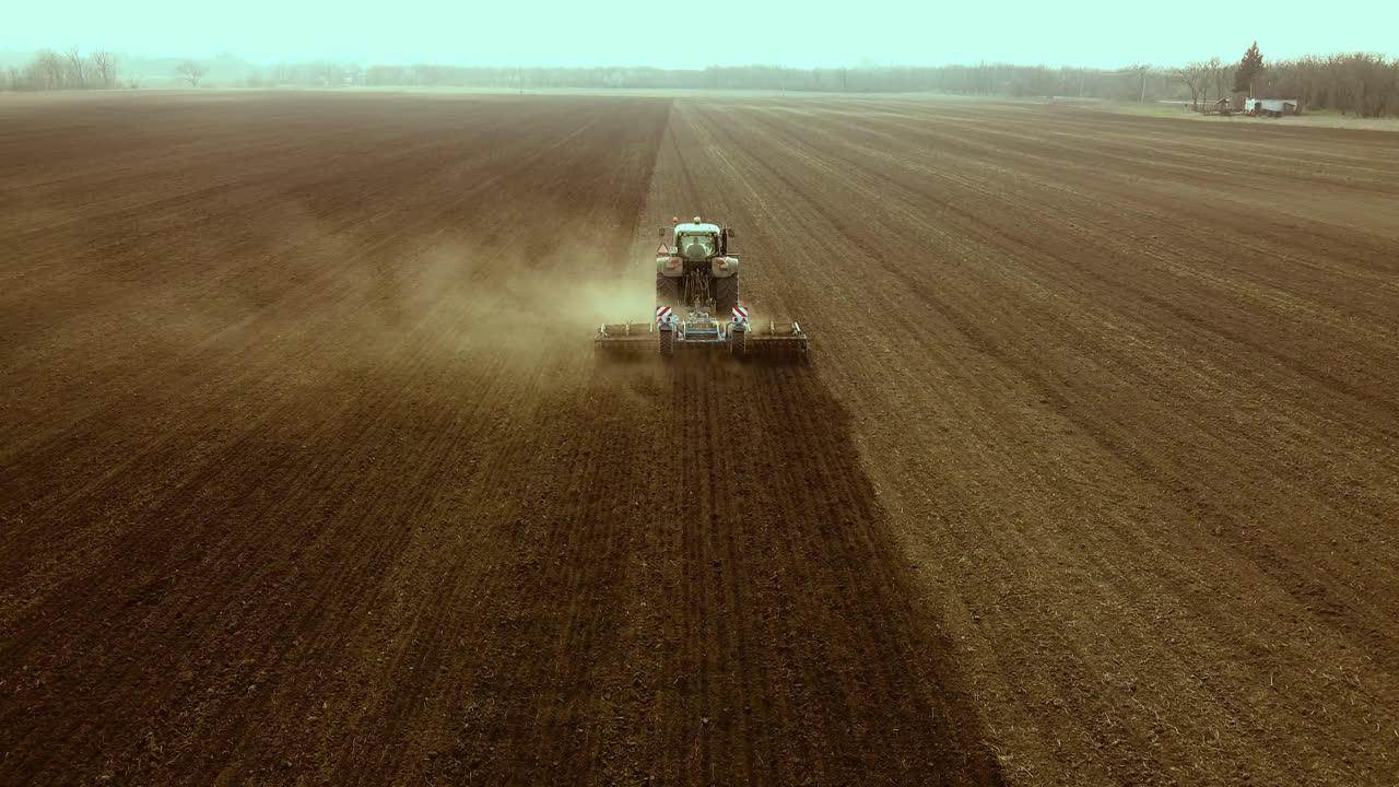 Un trattore lavora su un'ampia terra semi-arida, ripresa con drone.