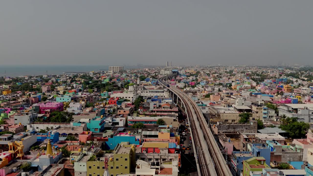 Drone shot of metro track passing through suburb city during daytime.
