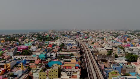 drone shot of metro track passing through suburb city during daytime.