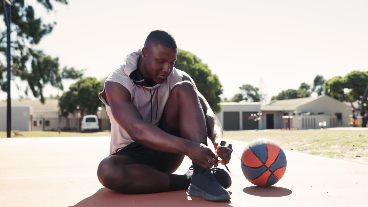 Mand binder sine snørebånd på en basketballbane