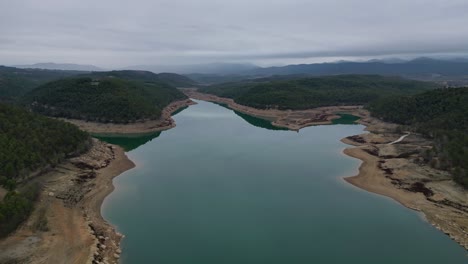 San-Ponce-Reservoir-in-Barcelona-with-calm-waters-and-surrounded-by-forested-hills-and-rugged-terrain