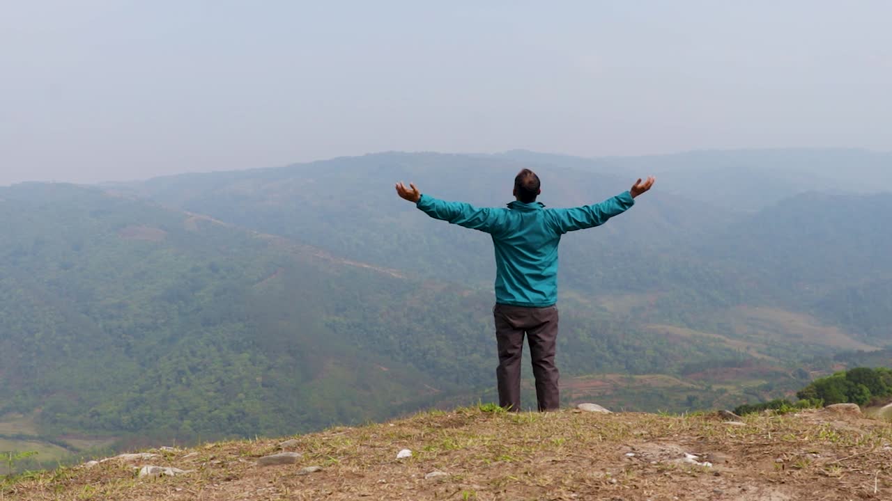 hombre caminando solo en la cima de una colina con un fondo de furia montañosa brumosa desde un video de ángulo plano tomado en nongjrong meghalaya india