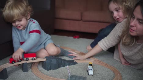 mother with kids playing with toy roadway