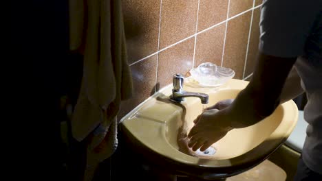 persona lavándose las manos en el lavabo del baño