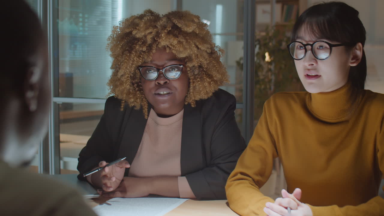 hombre de negocios hablando con diversas colegas femeninas en una reunión nocturna de la oficina