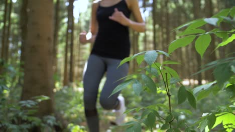 Woman-running-off-road-in-a-park-passes-near-the-camera-as-it-slides-left