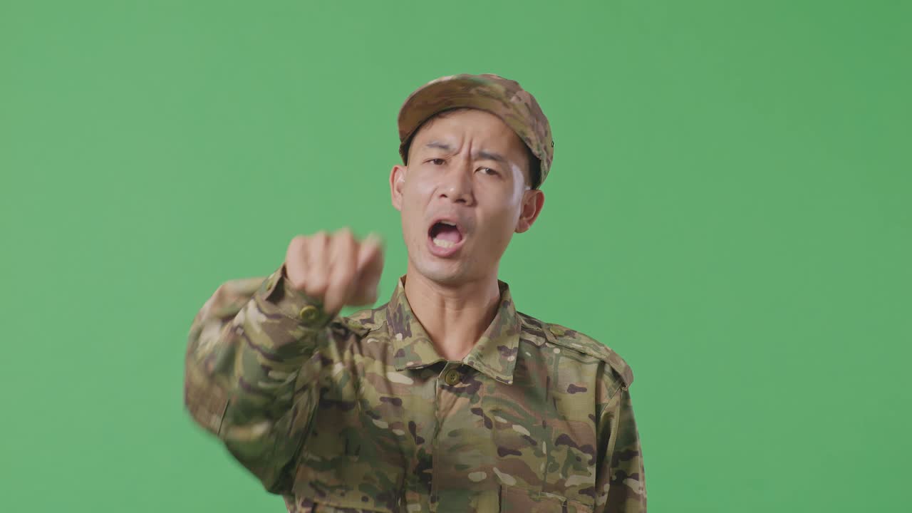 Close Up Of Asian Man Soldier Shouting To Camera While Standing In The Green Screen Background Studio
