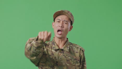 close up of asian man soldier shouting to camera while standing in the green screen background studio