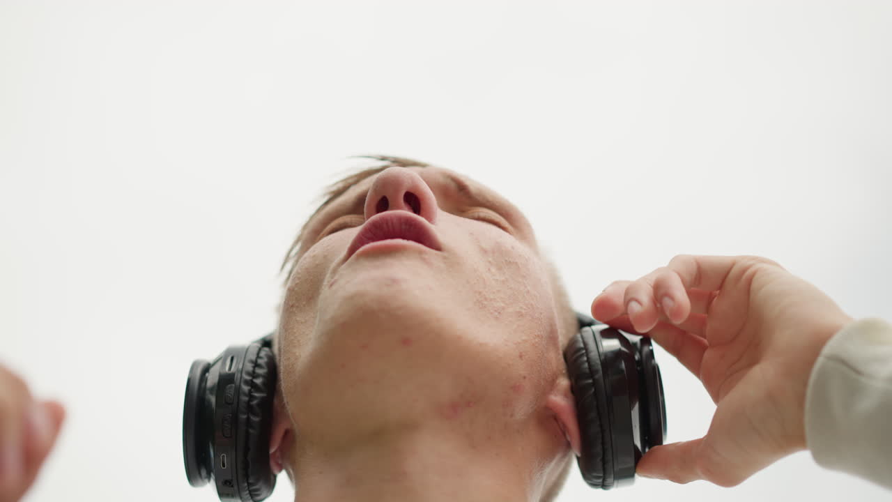 joven blanco mirando al cielo con auriculares bajo la lluvia, liberación épica y catártica mientras el oyente levanta la cara hacia el cielo nublado, director de coro, artista, celebrante y soñador esperanzado, emociones dramáticas