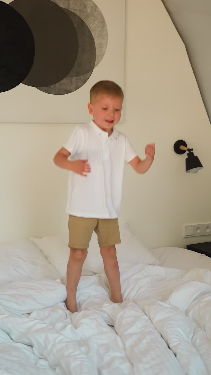 ребенок прыгает высоко на кровати в роскошном кемпинге. радостный маленький мальчик играет на мягком матрасе в гламурной спальне. веселый ребенок развлекается в огромной гостиничной палатке
