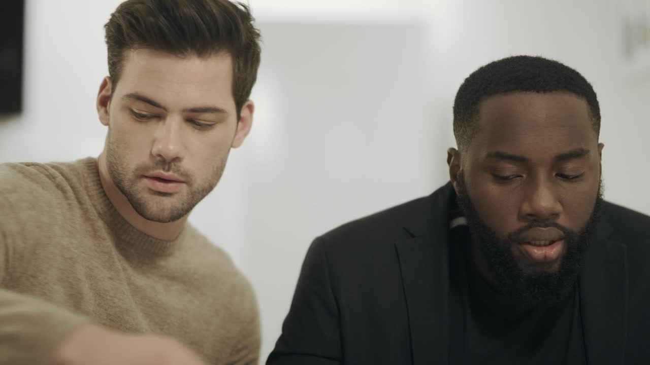 dos hombres de negocios discutiendo datos de trabajo sentados en un lugar de trabajo remoto.