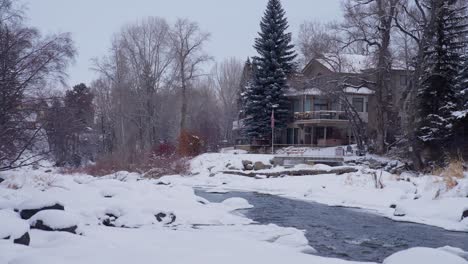 House-by-the-Creek-and-White-Cold-Winter-Landscape,-Snow-on-Fields-and-Forest