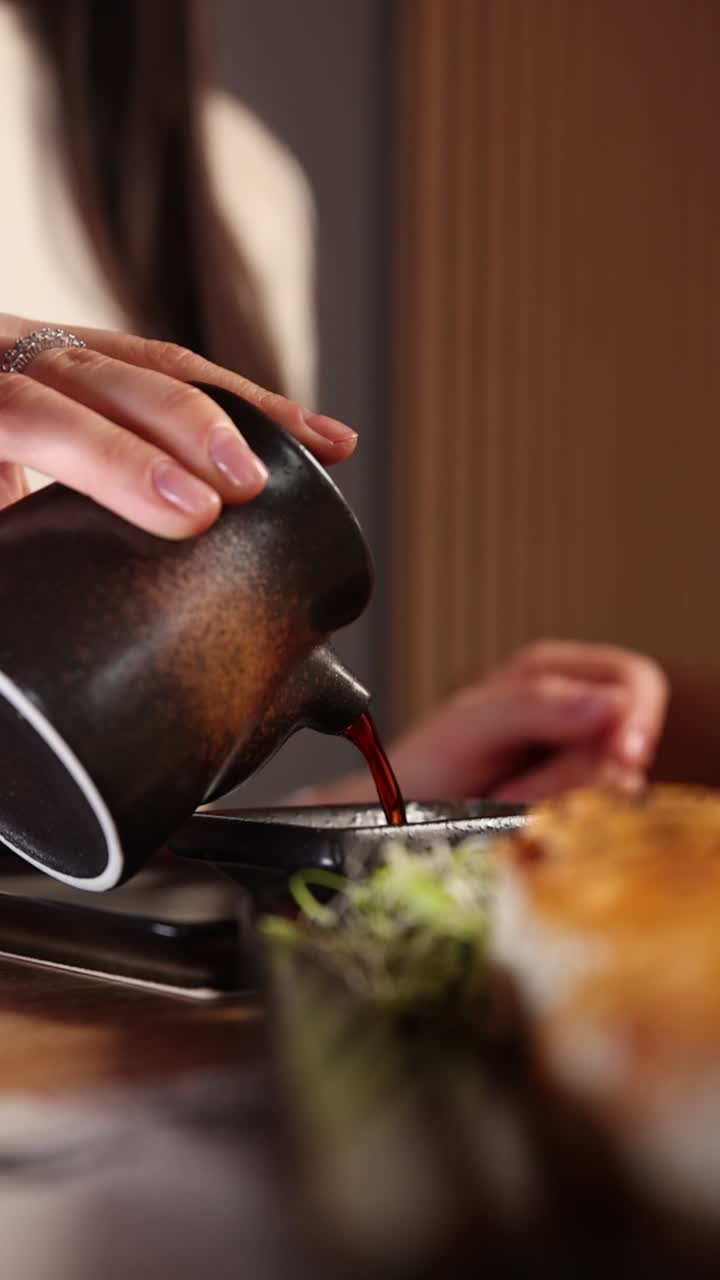 Close-Up of a Hand Pouring Sauce from a Ceramic Pitcher