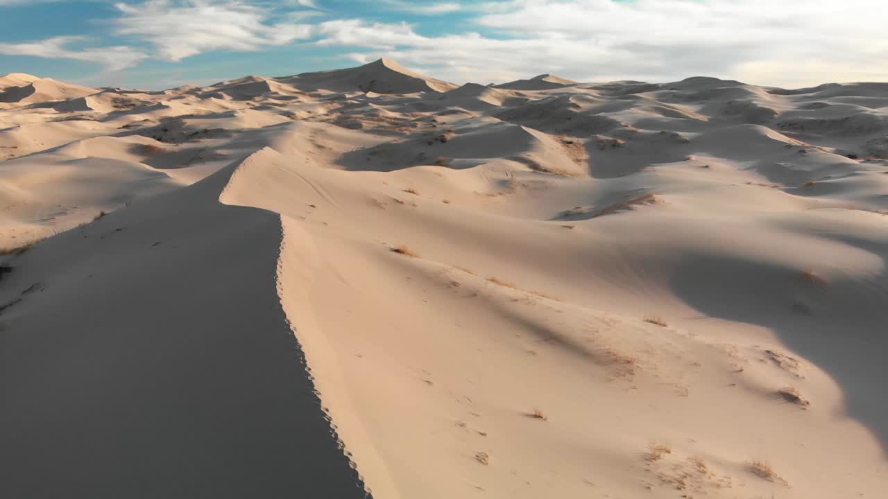 disparo aéreo de drones volando sobre la cresta de una duna de arena con pasos en el desierto mexicano