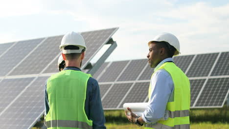 three multiethnics farm solar engineers talking on solar plantation