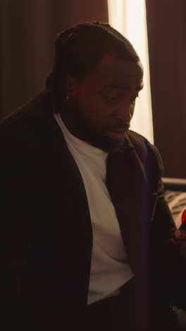 vertical video close up of confused man sitting on sofa after drinking alcohol at house party suffering with hangover