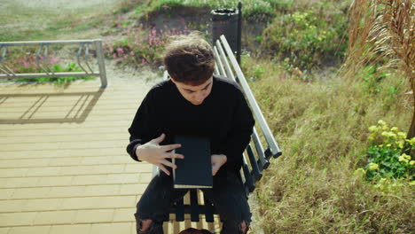 man closing his notebook at the park and putting it in the backpack