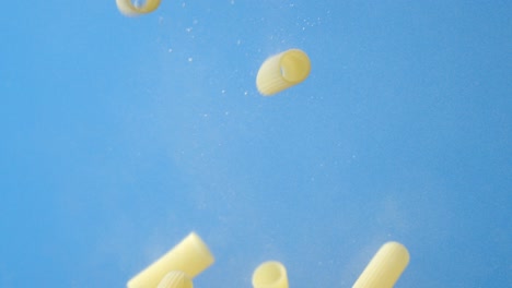 dry pasta cannelloni falls under water with air bubbles.