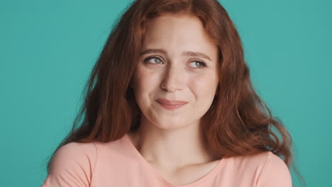 redheaded girl in front of camera on turquoise background.