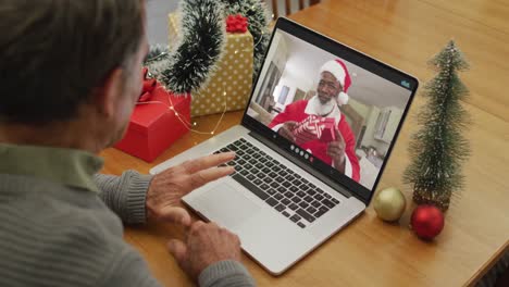 Caucasian-senior-man-on-video-call-on-laptop-with-santa-claus-at-christmas-time