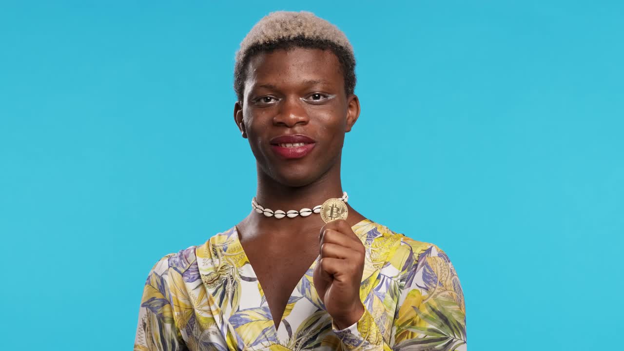 Transgender man holding and showing a bitcoin coin standing on an isolated background.